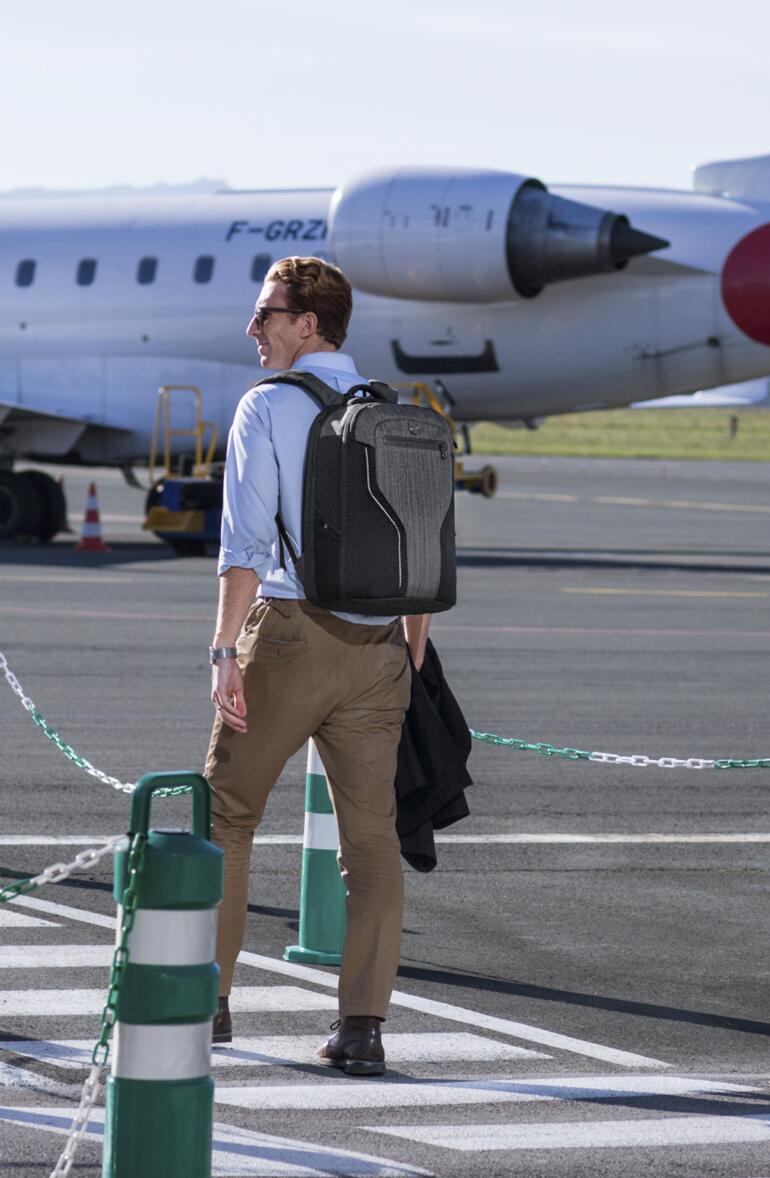 Man met rugzak op de luchthaven voor een vliegtuig.