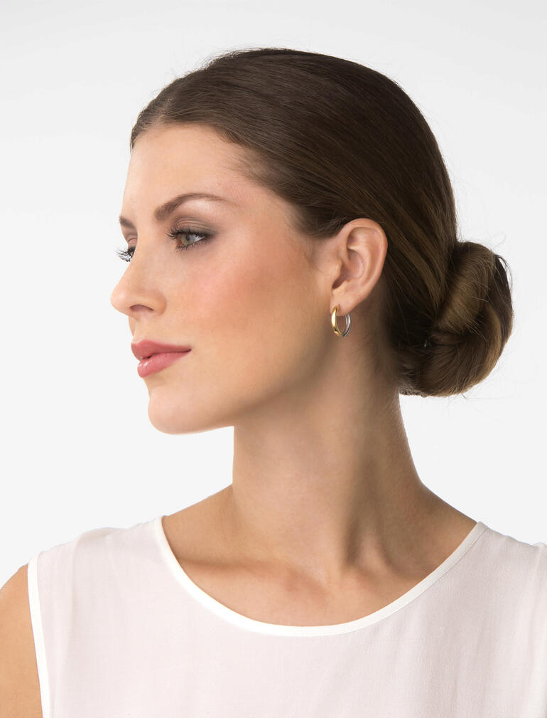 Vrouw met bicolor oorbellen die zijdelings in de camera kijkt.