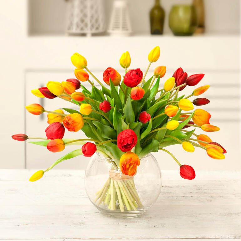 geel/oranje/rood Kleurige tulpenboeket in een ronde glazen vaas.