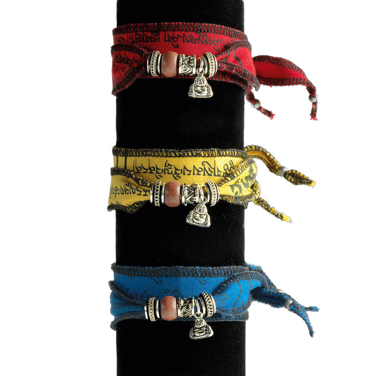 Drie Tibetaanse wensarmbanden in rood, geel en blauw met zilveren bedels.