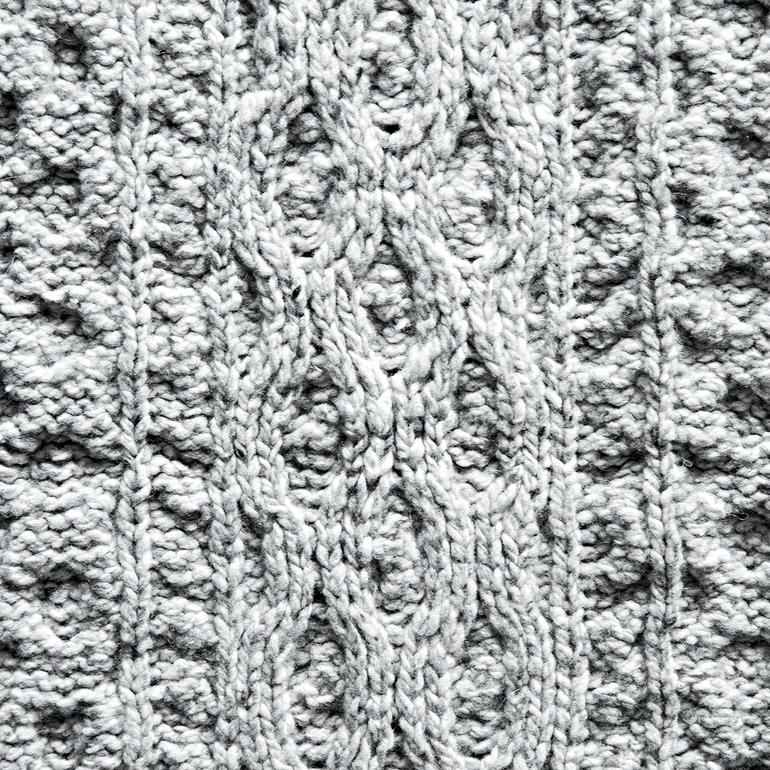 Close-up van het breipatroon van een grijs plaid.