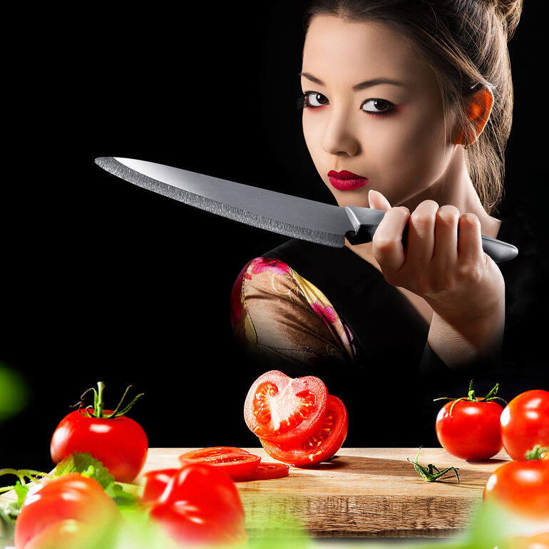 Messen van zirconium-keramiek Persoon met keramisch zirconium mes snijdt verse tomaten op een snijplank.