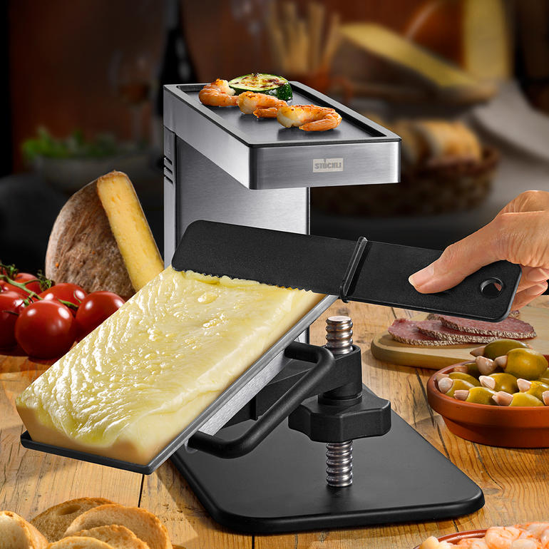 Raclette-grill met stuk kaas, groenten en vis op de grillplaat.