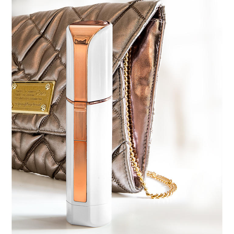 Door zijn discrete lipstick-design ideaal voor in de handtas. Gezichtsraser Roxy Pocket Shaver naast een modieuze handtas.