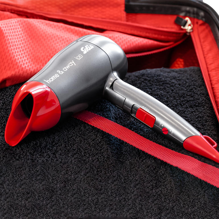 Solis compacte haardroger met rode handgreep in de bagage.