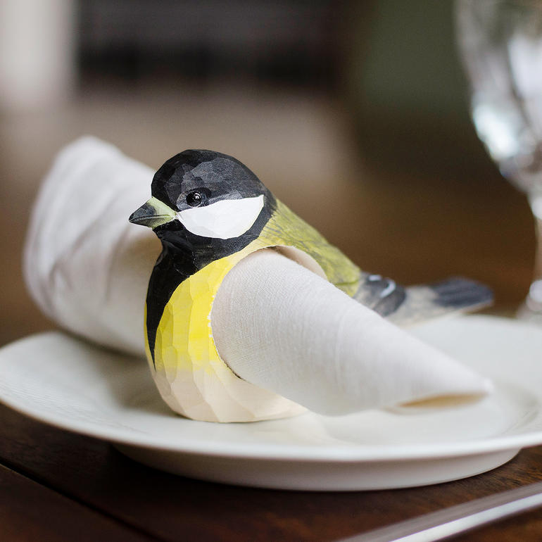 Kleurige servetring in de vorm van een vogel op een wit bord met een servet.