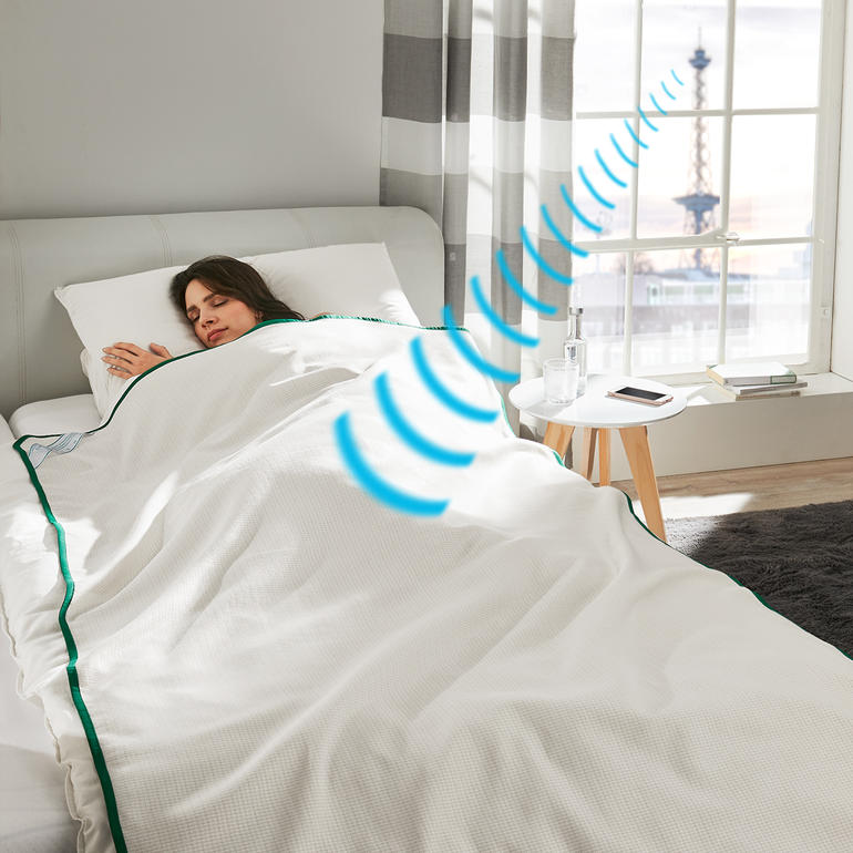Vrouw slaapt onder de Sleep Safe® afschermdeken in een moderne slaapkamer.