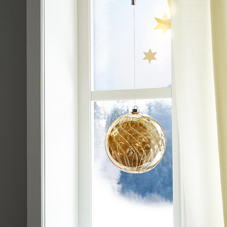 Decoratief om op te hangen of neer te leggen. Overdag glanst het getinte glas als een kostbare barnsteen. Getinte glazen bal met micro-LED's hangt aan het raam