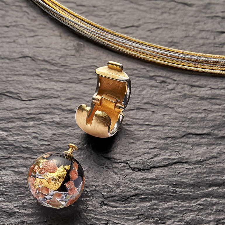 Met behulp van de clipsluiting kunt u het kraaltje van muranoglas snel en eenvoudig verwisselen. Haak en een verwisselbare Murano-glasparel op zwarte achtergrond.