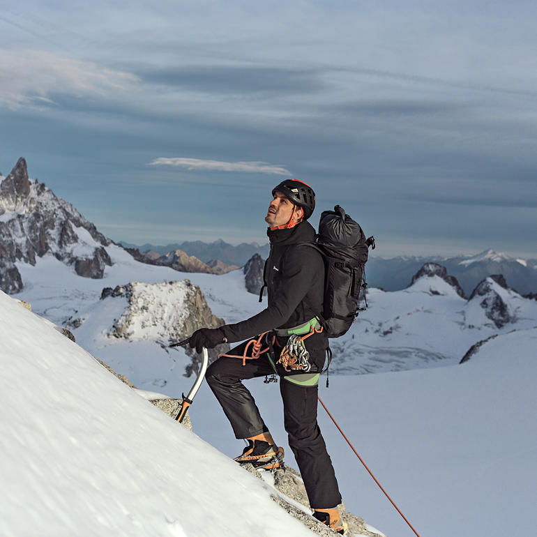 Man in Berghaus ThinDown-jacke terwijl hij een berg beklimt