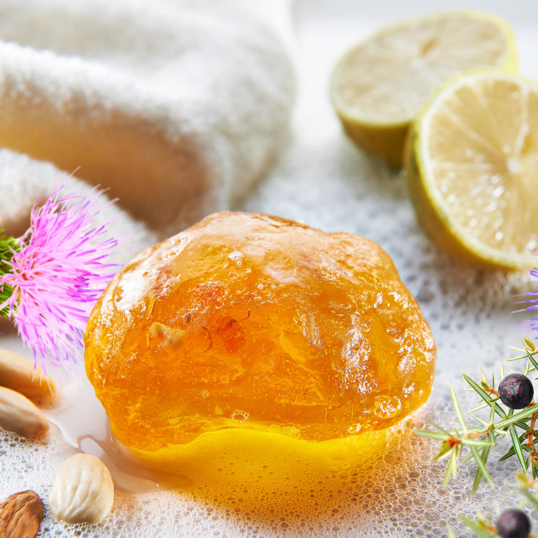 Bernsteinzeep met citrusvruchten en bloemen op een handdoek.