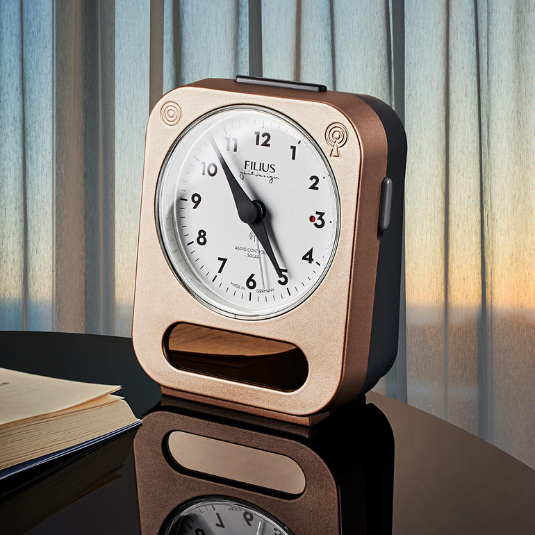Zonne-gestuurde wekker met een witte wijzerplaat en een bruine behuizing op een tafel