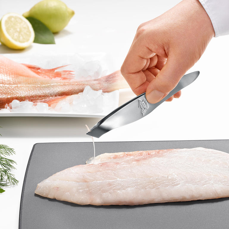 Hand verwijdert een graat met een KAI gratenpincet.