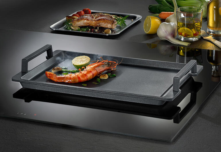 Teppanyaki-plaat met garnalen en groenten op een kookplaat.