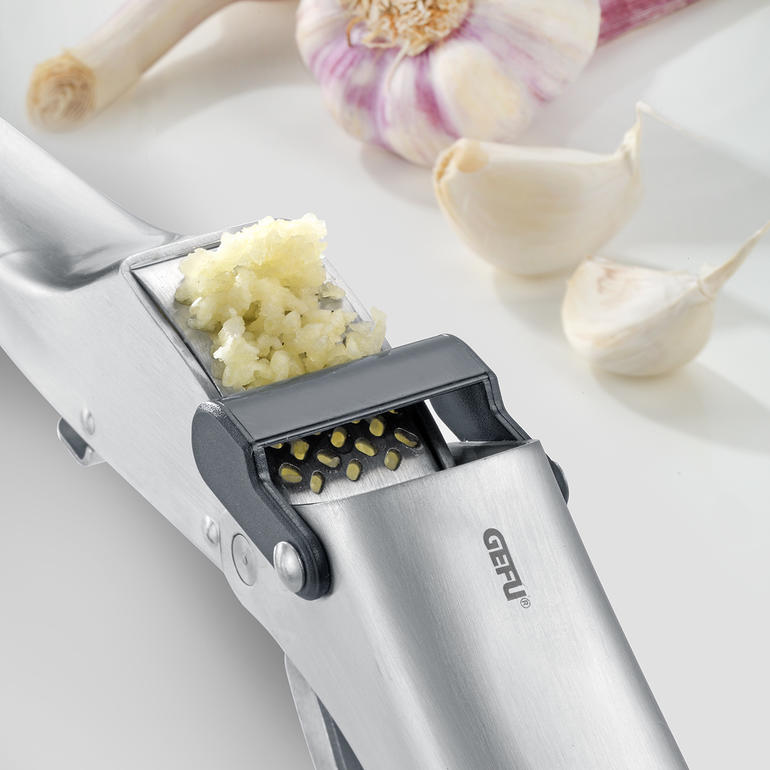 Knoflookpers Garlico Knoflookpers met geperste knoflook naast hele tenen