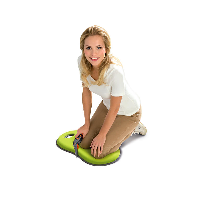 Vrouw knielt op een groen kniel- en zitkussen in de tuin.