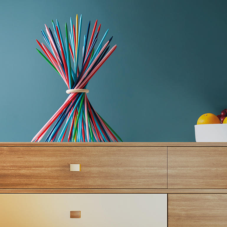 Kleurrijke XXL-sticks in een artistieke schikking op een houten tafel.