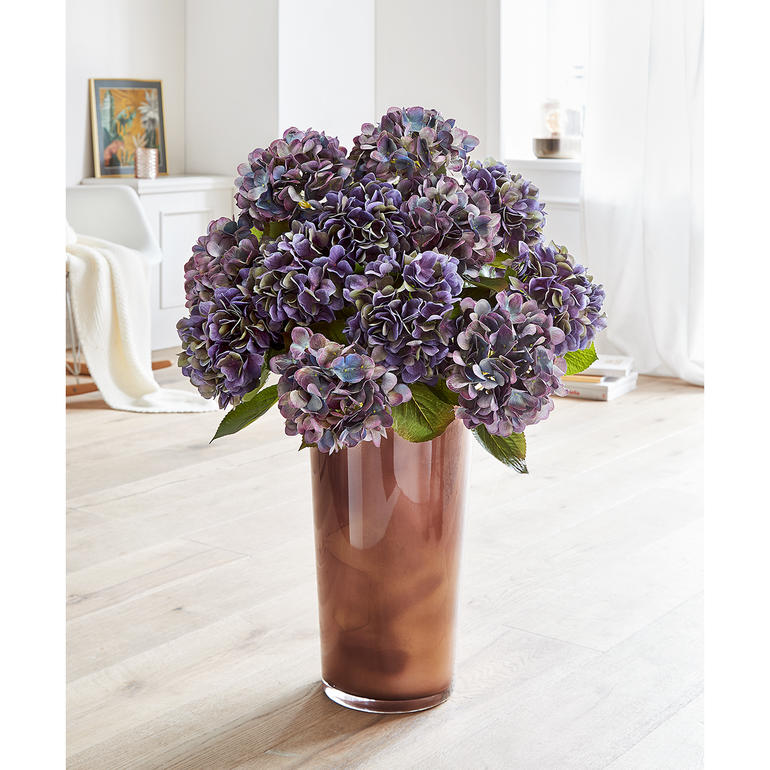 Een schitterend arrangement dat mooi past bij alle lichte en donkere interieurkleuren. Kleurrijke hortensia in een boeket in een doorzichtige vaas.
