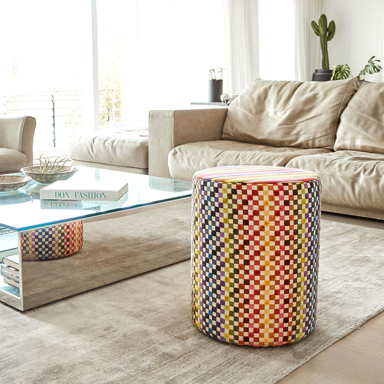 Kleurige Missoni-zithocker naast een gezellige bank in de woonkamer.