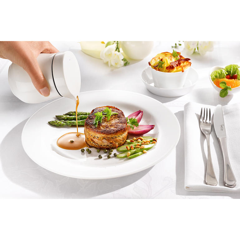 Vrouw serveert saus met een thermo-sausser op een bord.