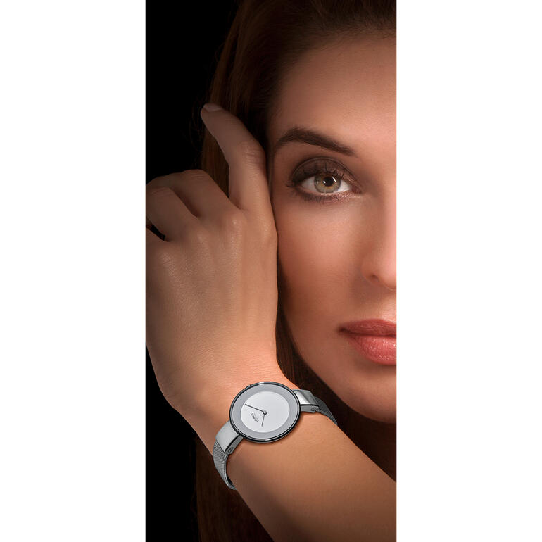 Horloge met milanaise-bandje Vrouw draagt een milanaise armbandenhorloge en kijkt naar de camera.