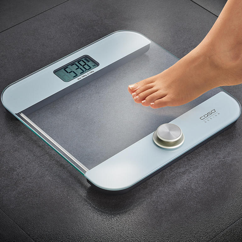 Batterijloze personenweegschaal met voet op een oppervlak.