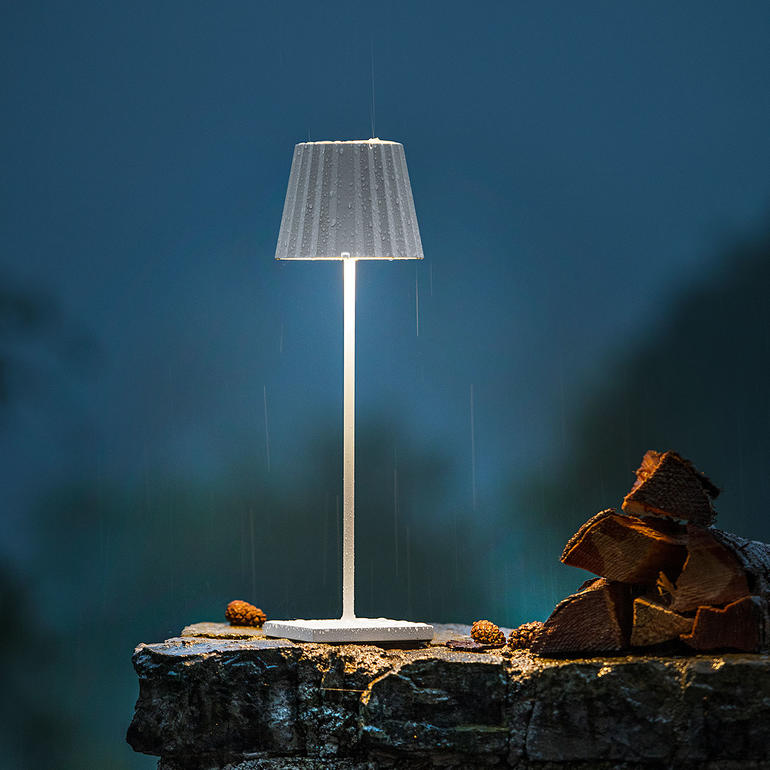 Design oplaadbare tafellamp met stijlvolle kap op een steen.