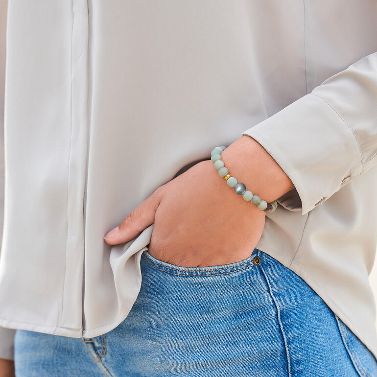De elegante, sierlijke armband kan worden gecombineerd met elke look, de hele dag lang. Close-up van een amazonietarmband om de pols van een vrouw