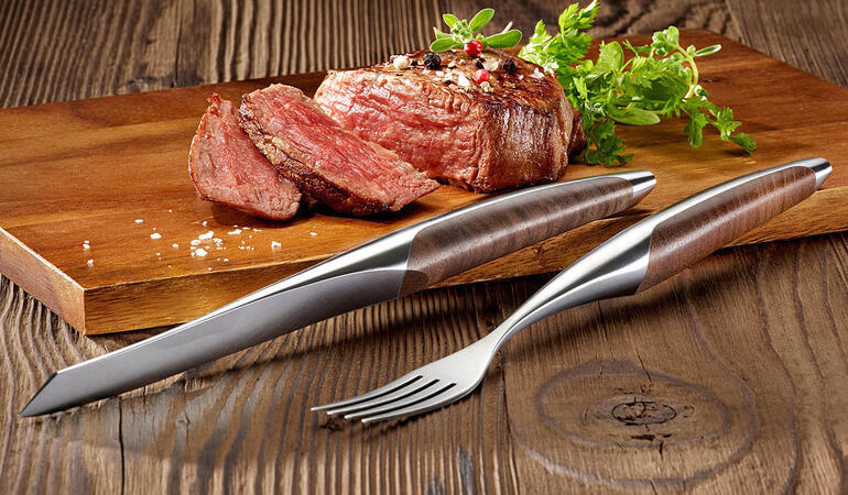 Steakmes en vork set geserveerd met een steak.