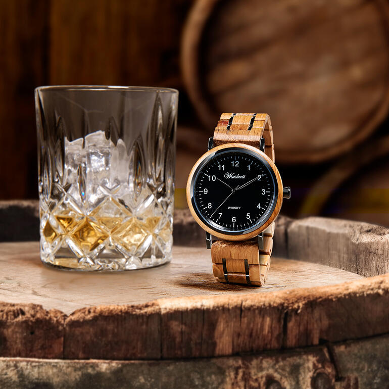 Herenhorloge van whiskyvaten naast een glas whisky