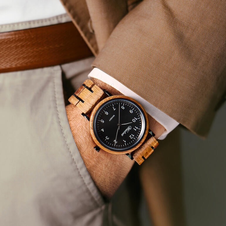 Een bijzondere, stijlvolle en unieke creatie voor om uw pols. Herenhorloge van whiskyvaten aan de pols van een man