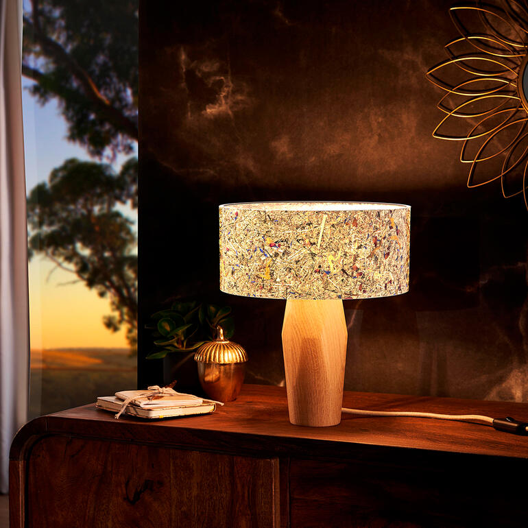 Moderne tafellamp van dennenhout met kleurrijke kap op een sideboard