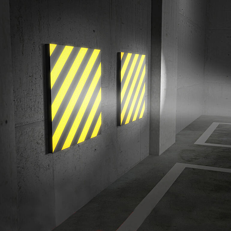 Invallend licht reflecteert heel helder op de geel/zwarte strepen – wat zorgt voor extra veiligheid bij het inparkeren. Twee garagewand kussens met geel-zwarte strepen tegen een muur.