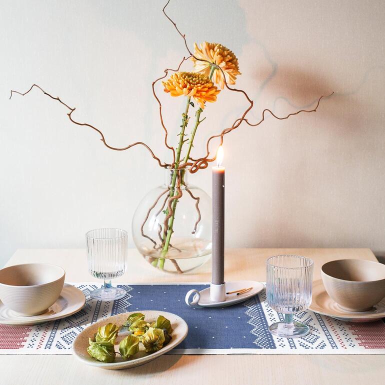 Tafel met Noorwegen tafelkleed, kaars en bloemenarrangement.