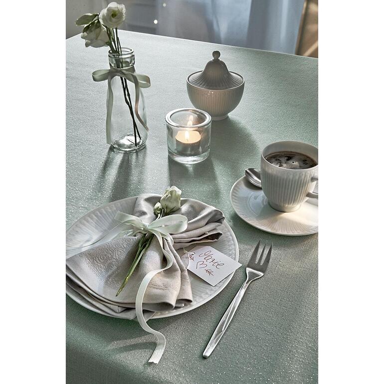 Tafel gedekt met feestelijk tafelkleed in linnenlook en bloemen.
