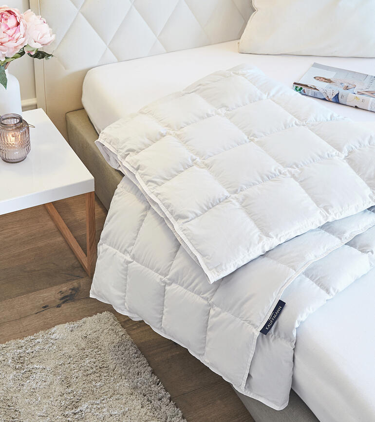 Lichte eiderdeken op een bed met kussens