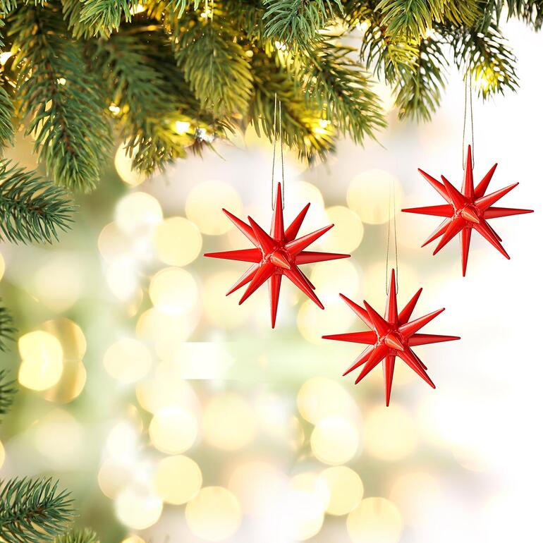 Drie rode Seiffener kerststerren hangen aan een versierde kerstboom.