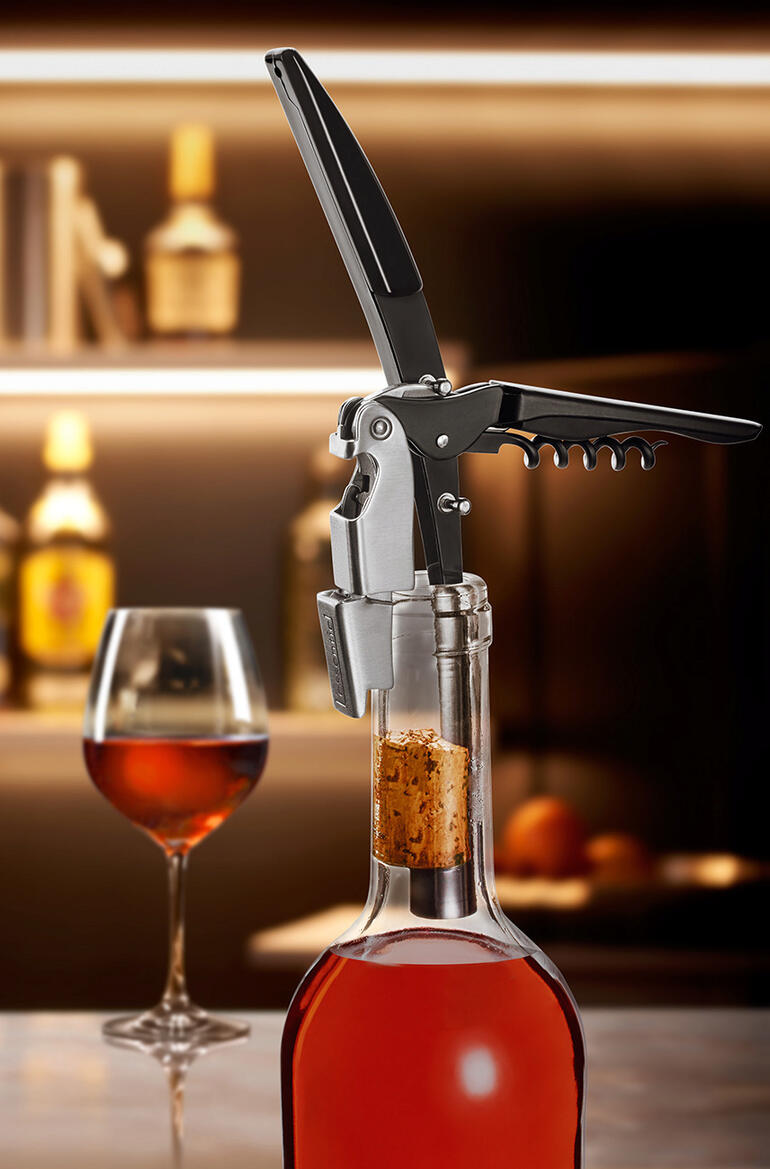 Fles wijn met een kurkentrekker, geplaatst op een tafel in een restaurantomgeving.