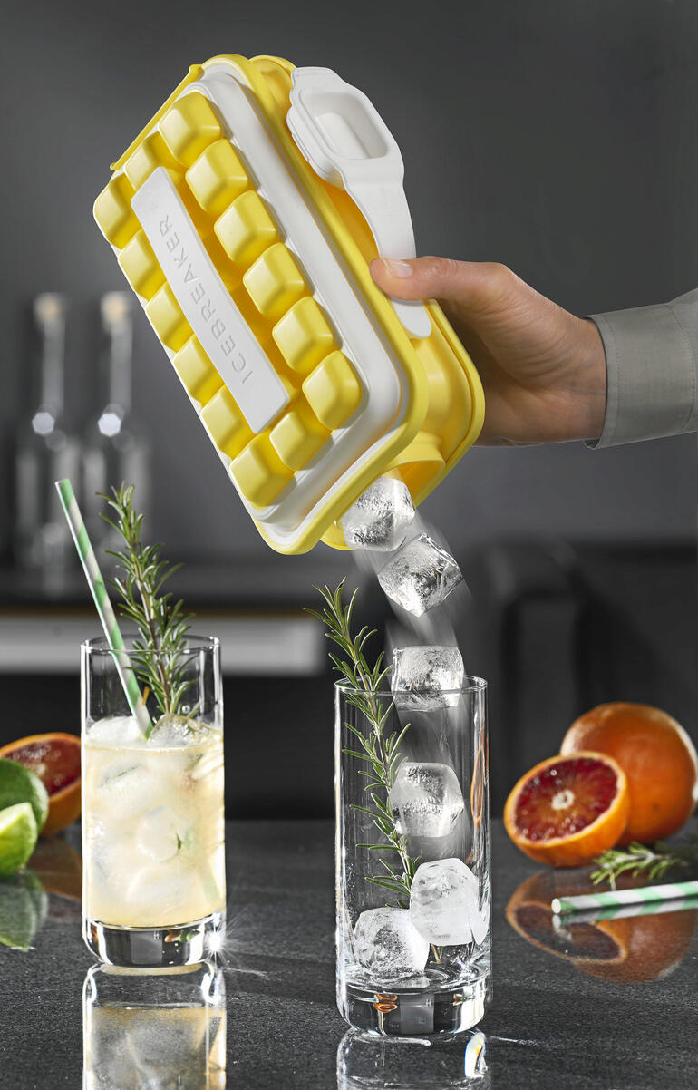 Hand houdt Ice-Pop ijsblokjesvorm, ijsblokjes stromen in een glas met drank.