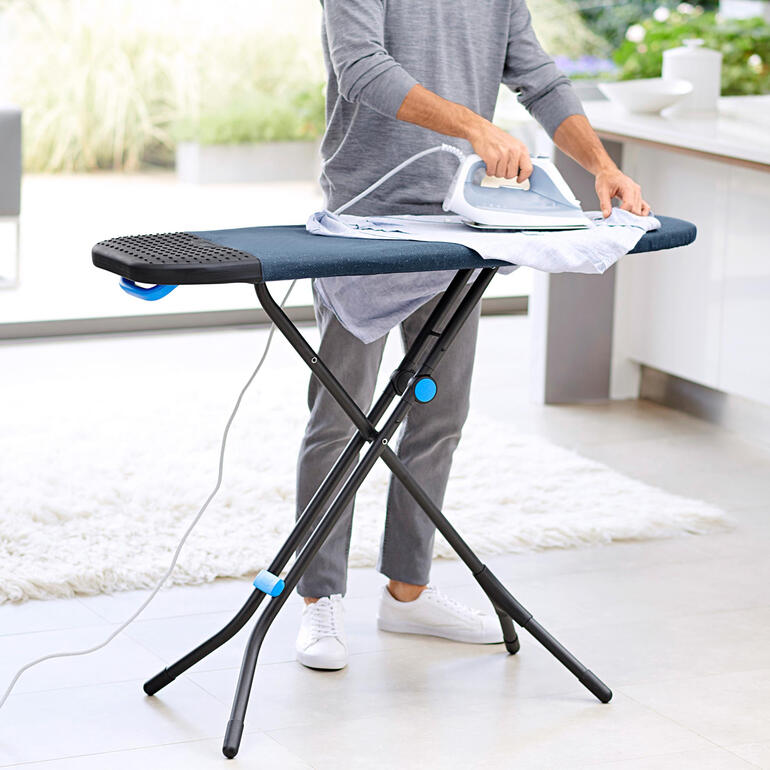 Man strijkt een overhemd op een Joseph Joseph Glide Plus strijktafel.