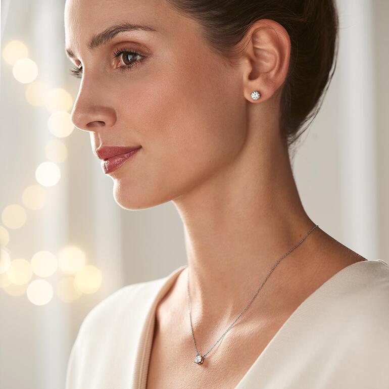 Vrouw draagt Moissanite juwelen: oorbellen en hanger