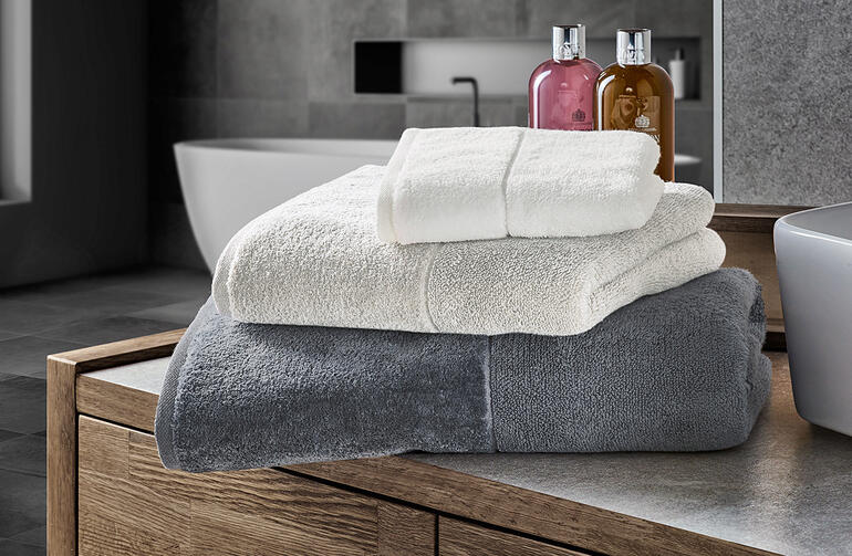 Lichte badhanddoeken in wit en grijs op een badmeubel