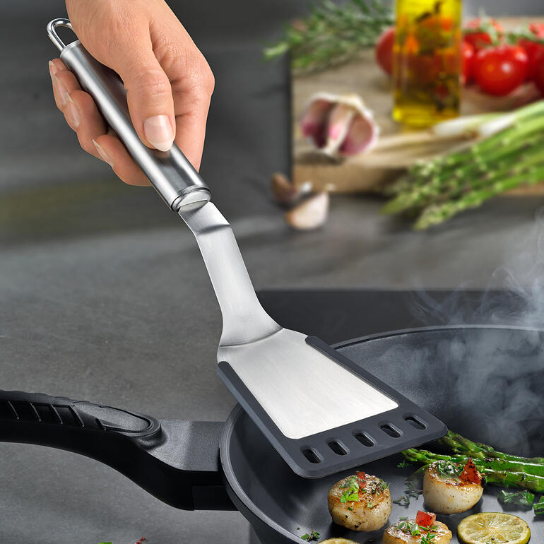 Afgebogen spatel wordt gebruikt om voedsel in een pan te keren.