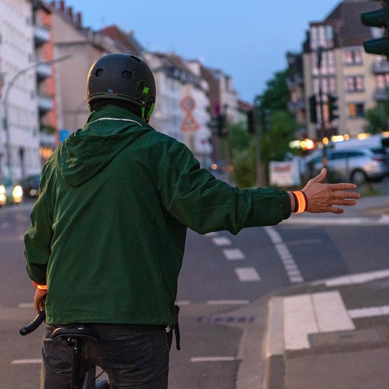 Fietser met een lichtarmband die een gebaar maakt.