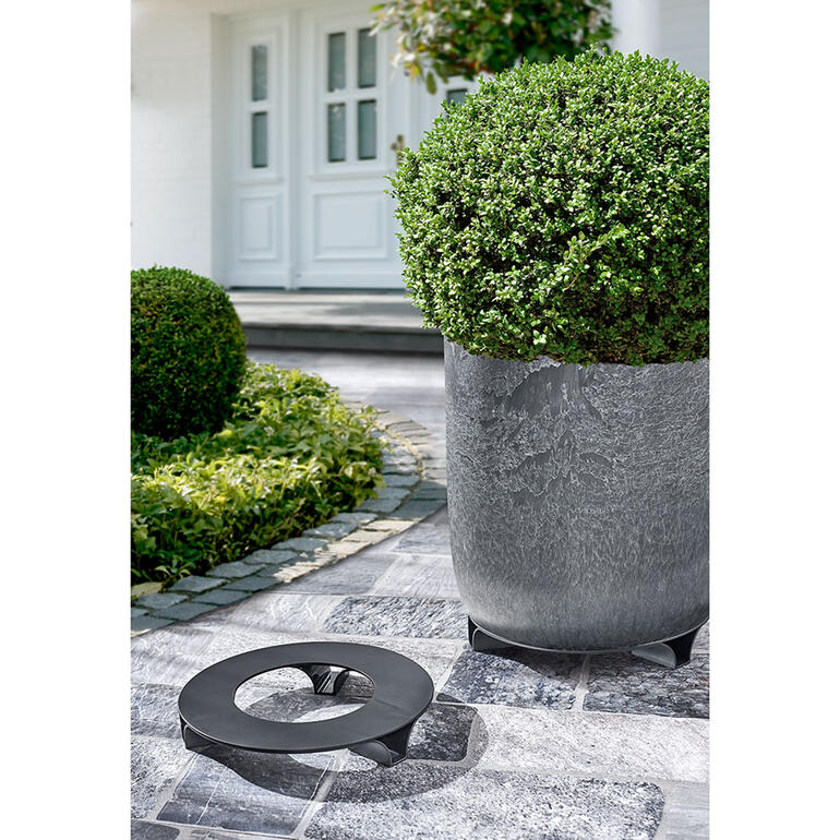 Stijlvolle bloempotten met schotels op een betegeld pad.