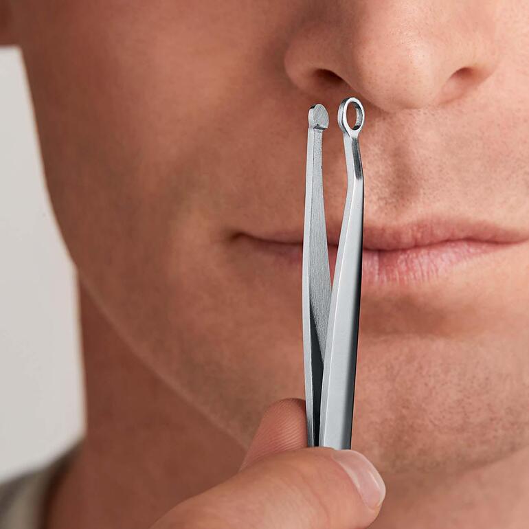 Man houdt een pincet voor haarverwijdering voor zijn gezicht.