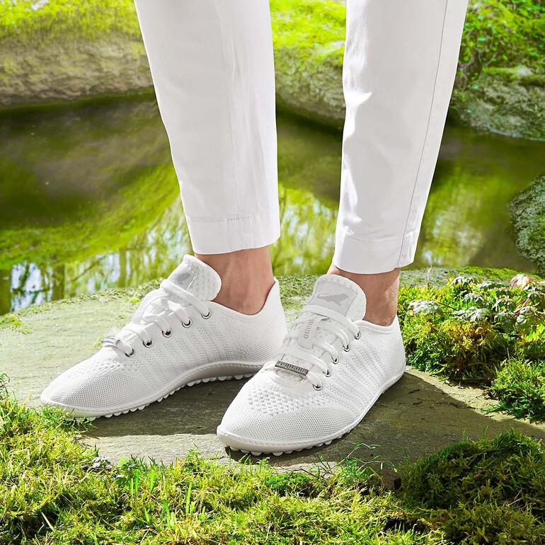 Barfuß-leguano Sneaker in wit, gedragen door een persoon.