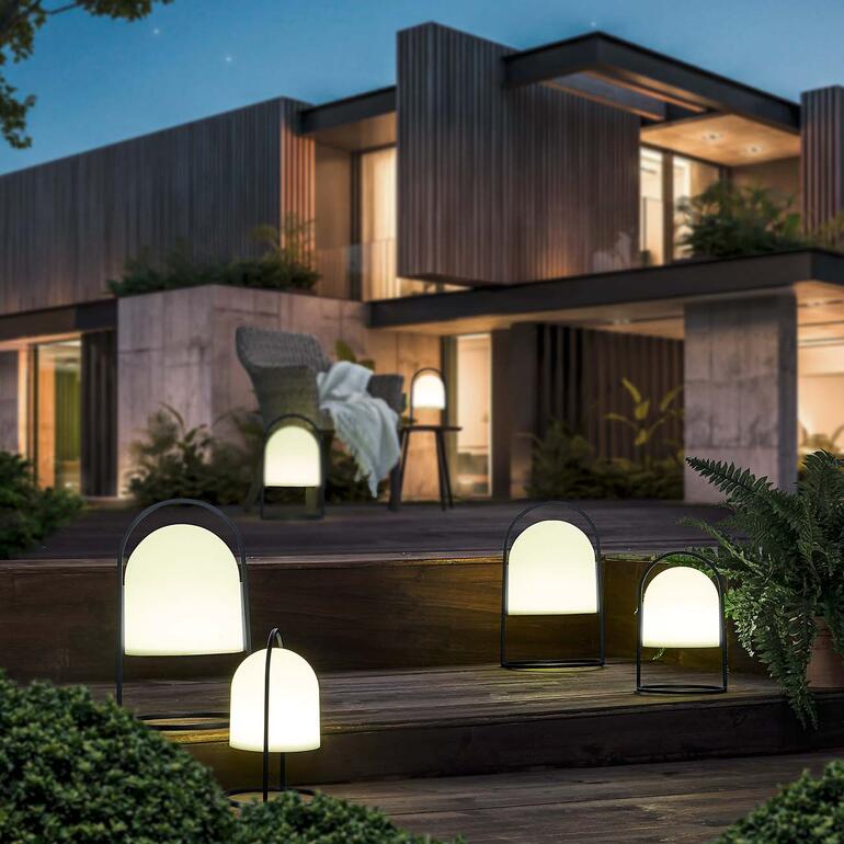 Zonne-lamp in een tuin voor een modern huis in de nacht.