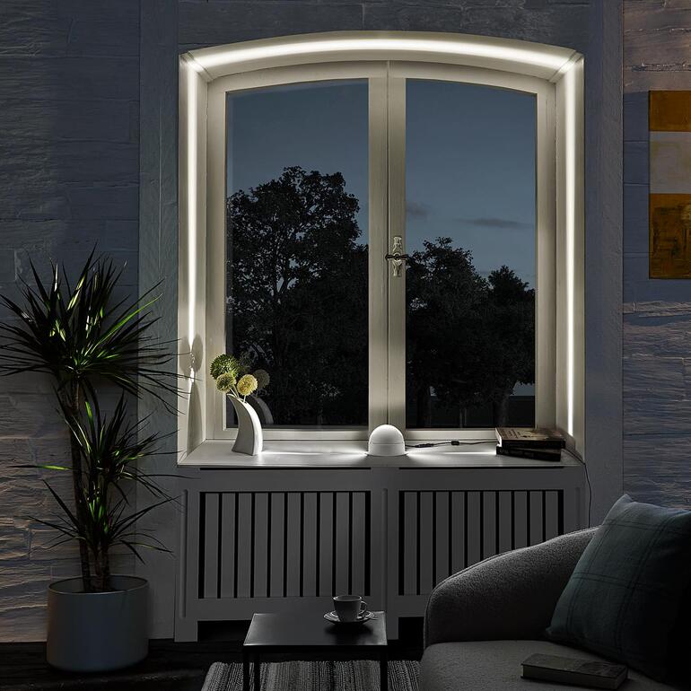 LED-raam-effectlamp bij een raam met uitzicht op een tuin