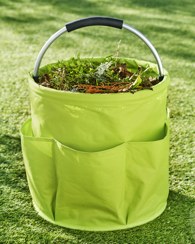 Perfect uitgerust met een extra groot middenvak van 28 l, 6 ruime buitenvakken en een sterke, gepolsterde aluminium handgreep. Tuin Caddy gevuld met plantenafval op groen gras.